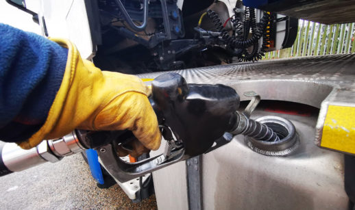 Detalhe de frentista com luva amarela abastecendo caminhão com diesel, que puxou alta do IGP-M de junho