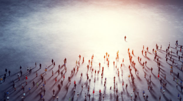 Líder na frente de outras pessoas caminhando em direção a local iluminado