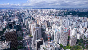 Aérea de São Paulo, com destaque para os prédios e céu azul com nuvens, alusivo à valorização dos fundos imobiliários