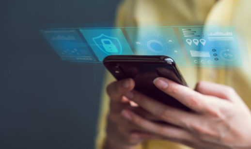 Close de celular nas mãos de uma pessoa com hologramas de segurança em cima, alusivo ao golpe do celular roubado