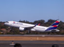 Avião da Latam, que está em recuperação judicial, decolando em pista de aeroporto com céu azul