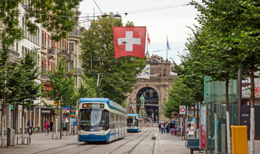 Rua de Zurique, onde fica o Banco Central da Suíça, com bonde andando e bandeira do país