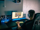 Menino de costas com fone de ouvido em frente ao computador jogando, alusivo à Futster