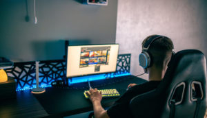 Menino de costas com fone de ouvido em frente ao computador jogando, alusivo à Futster