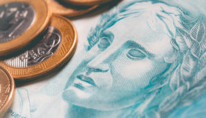 Detalhe de nota de real e moeda, alusivo à dívida pública federal