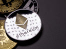 Conceito da moeda Ethereum, na cor prateada, sobre outros criptos em mesa cinza