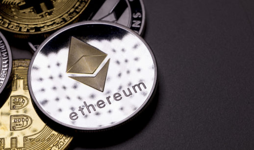 Conceito da moeda Ethereum, na cor prateada, sobre outros criptos em mesa cinza