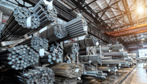 Vigas de aço juntas e penduradas dentro de galpão, alusivo às atividades da Gerdau