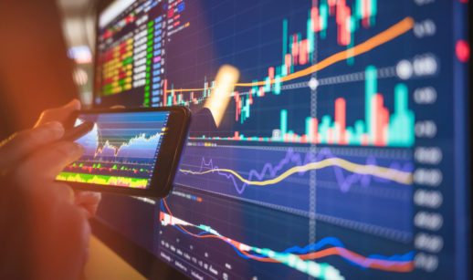 Close de telas de celular e computador com gráficos de ações, alusivo às top picks do Safra