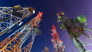 Perspectiva de baixo para cima de torres de telefonia móvel, alusivo à venda da Oi para a Highline