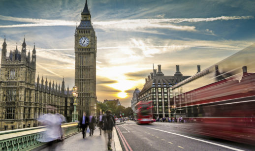 Ponte de Londres com Big Ben ao fundo e ônibus vermelho em movimento, alusivo à subida dos juros do Reino Unido para combater a inflação