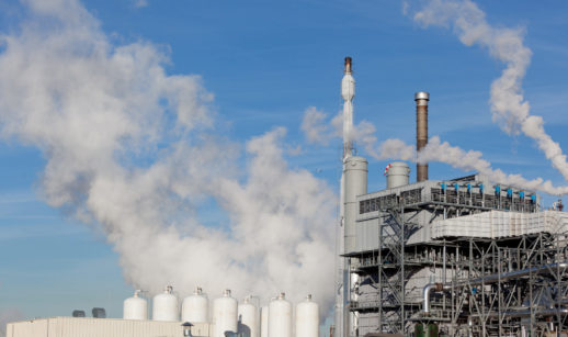 Chaminés de fábrica soltando fumaça branca, alusivo à cadeia produtiva com hidrogênio