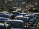 Tráfego de veículos em Salvador, na Bahia, com pôr do sol e casas bem ao fundo, alusivo ao volume de financiamento de veículos