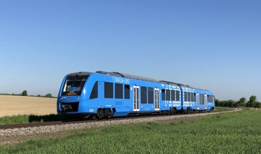Trem da Alstom movido a hidrogênio que está na Alemanha na cor azul, em trilho com céu azul e gramado verde no entorno