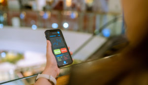 Close de celular na mão de pessoa de costas com tela de mercado financeiro aberta, alusivo ao crédito privado de setembro