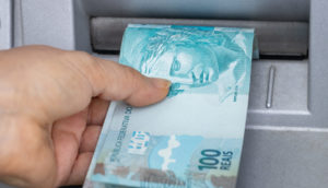 Mão puxando duas notas de 100 reais, alusivo ao saque do golpe do FGTS