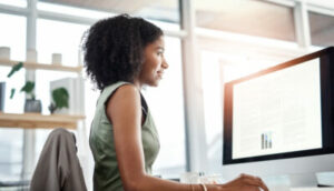 mulher observa gráficos na tela do computador, alusivo a um candidato da certificação ancord