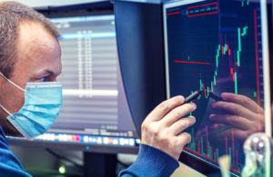 Investidor analisa gráficos financeiros em telas de computador