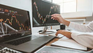 Investidor analisa gráfico em dois monitores de computador