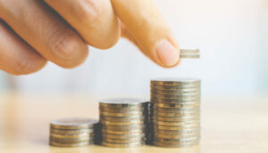 mão empilhando moedas, alusivo as vantagens da portabilidade de previdência privada