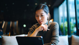 Pessoa sentada em um ambiente interno moderno, utilizando um tablet sobre a mesa